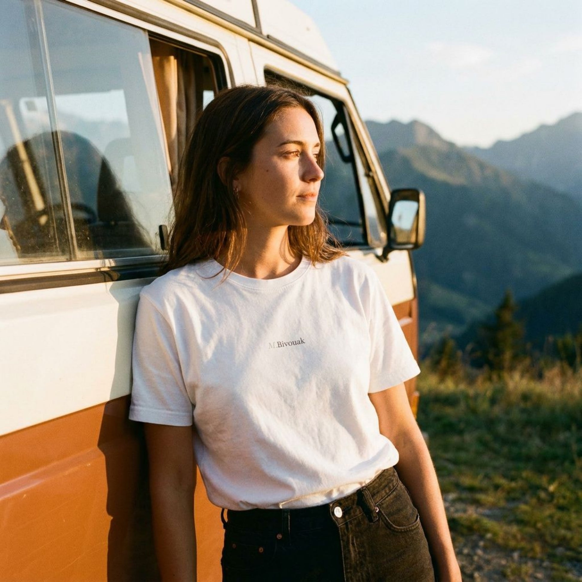 Femme portant le t-shirt M.Bivouak blanc en coton en conversion biologique devant un combi VW en montagne. Vanlife.