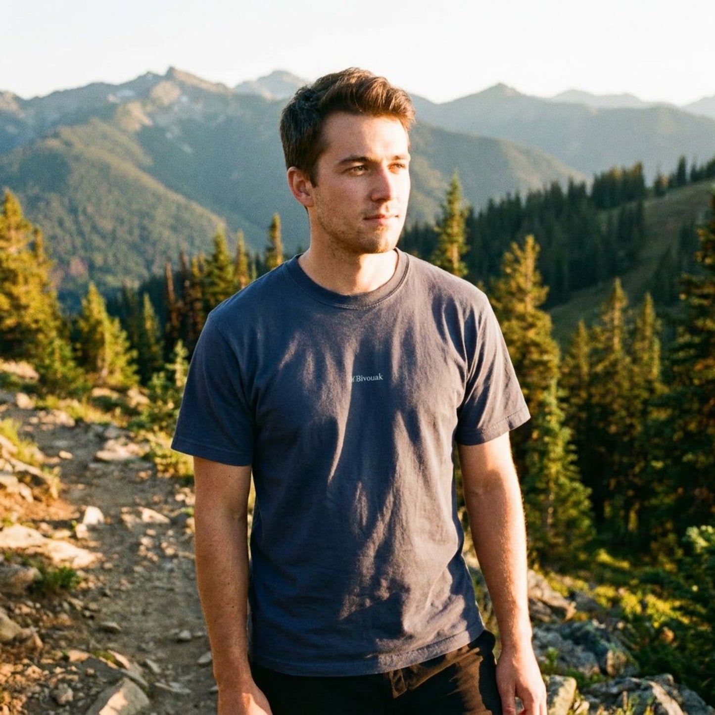 Homme en randonnée portant le t-shirt M.Bivouak bleu marine en coton en conversion biologique en montagne. Vanlife.